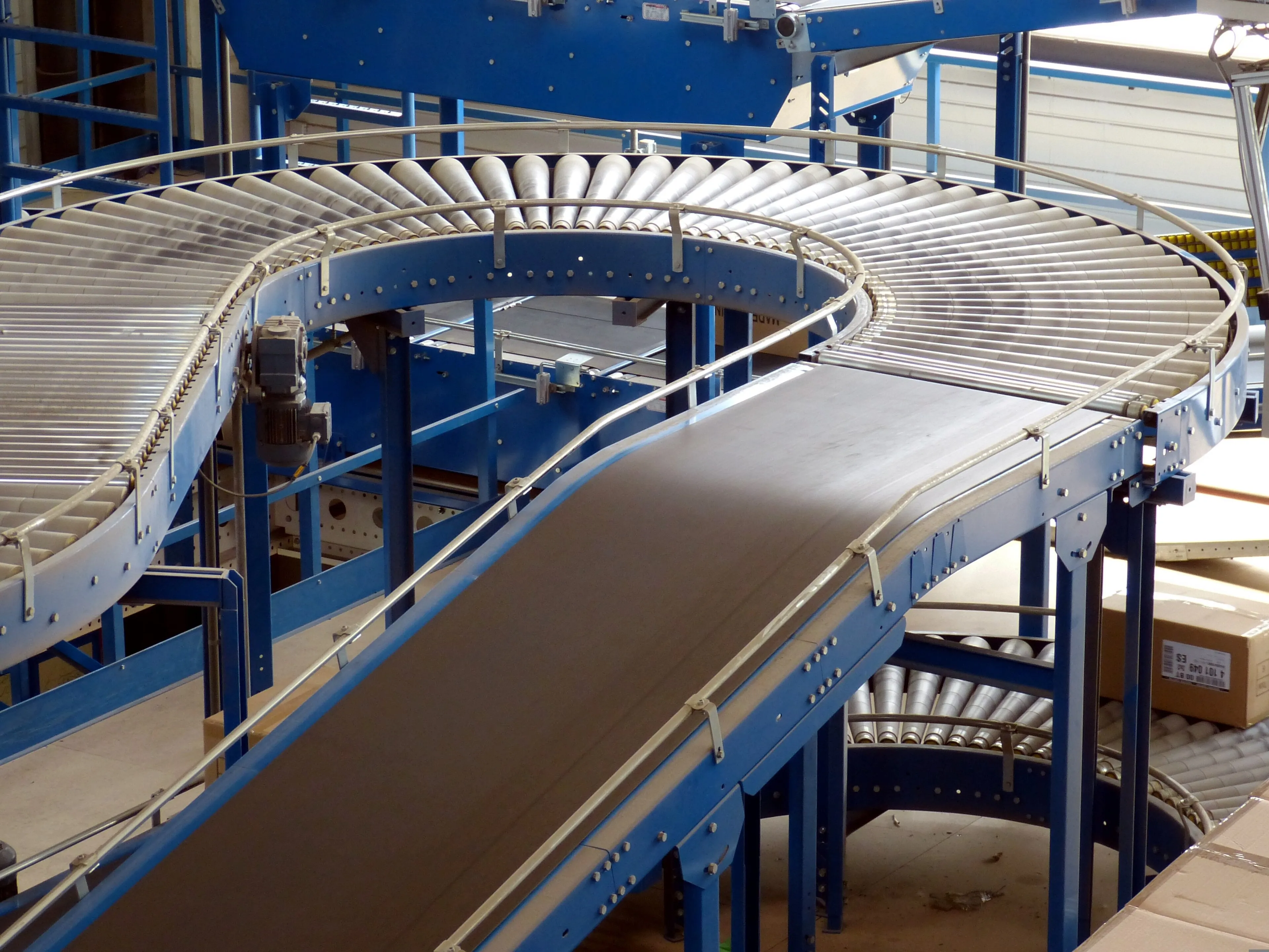 Roller and belt conveyors curving through an industrial hall